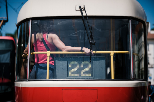 Bus driver visible through windshield wearing red shirt and yellow safety vest, route number 22 displayed on window.