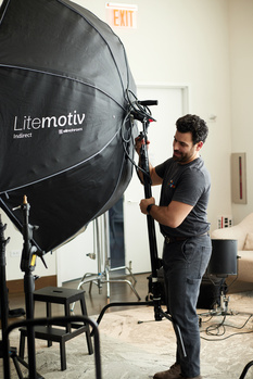 Photographer adjusting a large black parabolic softbox in an indoor studio setting.