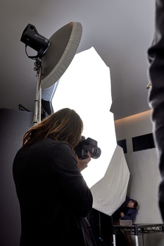 Photographer adjusting a large softbox light modifier mounted on a stand during studio setup.