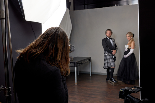 Photographer shooting a formal portrait session with two subjects in Scottish formal wear in a studio setting.