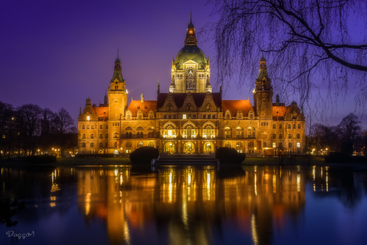 Illuminated Gothic Revival castle reflected in still water at twilight.