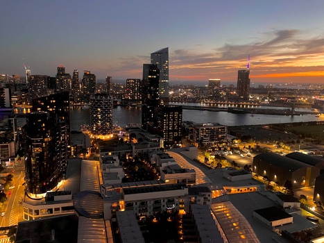 Manhattan skyline at dusk with illuminated buildings reflecting golden hour light across the East River.
