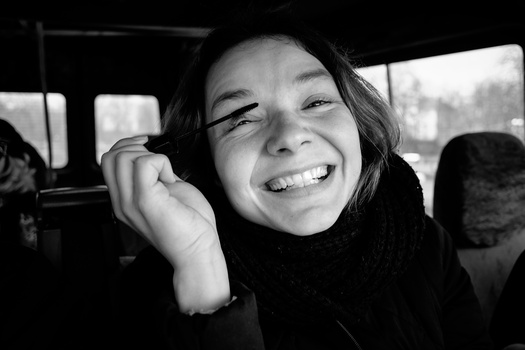 Young person smiling broadly inside a vehicle, captured in black and white portrait photography.