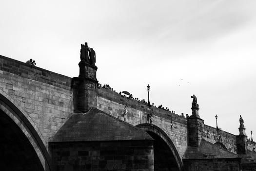 Historic stone bridge with ornamental statues and lamp posts in black and white.