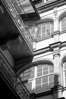 Architectural facade shot upward showing stacked windows and ornamental railings in black and white.