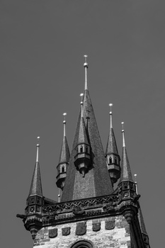 Black and white architectural photograph of an ornate castle tower with multiple spires against a gray sky.
