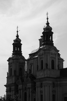 Two ornate church domes with crosses silhouetted against an overcast sky in black and white.