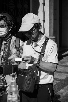 Cinematographer holding professional video camera at night, wearing white cap and utility vest.