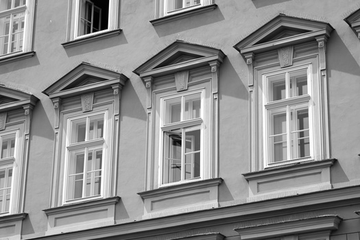 Black and white photograph of classical building facade with three tall windows and triangular pediments.
