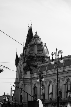 Historic ornate building with peaked tower and detailed architectural stonework against overcast sky.