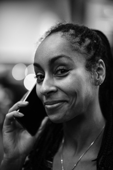 Woman speaking on a phone with a slight smile, photographed in black and white profile.