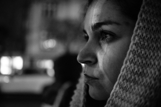 Woman in profile against textured wall, shot in black and white with dramatic side lighting.