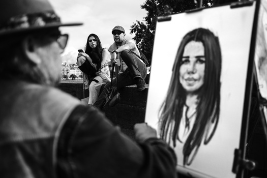 Photographers observe a large portrait photograph displayed outdoors during what appears to be a photo shoot or exhibition setup.
