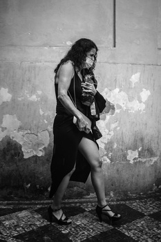 Woman in black dress posing against weathered concrete wall in black and white portrait.