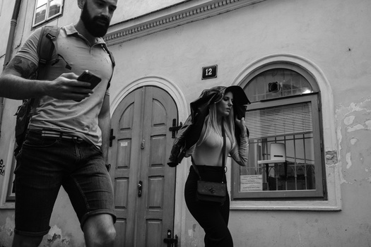 Two people jogging past a weathered building facade in black and white street photography.