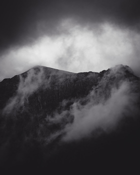 Misty mountain landscape with dramatic storm clouds in black and white.