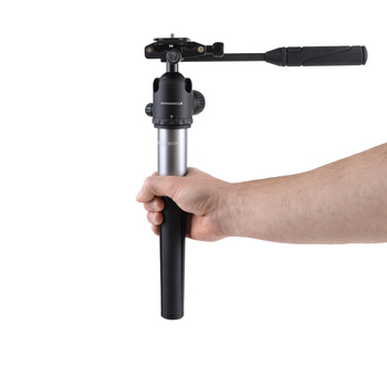 Hand holding a fluid head tripod with pan handle extended horizontally.