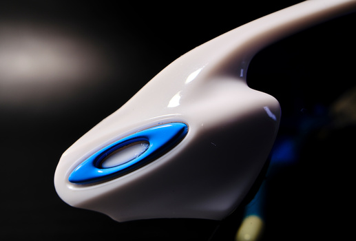 Close-up of a white computer mouse with a glowing blue oval button, photographed against a dark background.