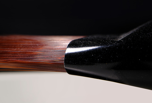 Close-up of a paintbrush with black ferrule and colorful bristles against a wooden surface.