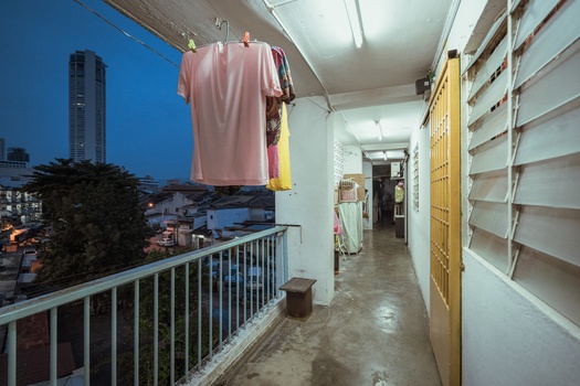 Laundry hanging from a clothesline on a narrow balcony overlooking an urban cityscape at dusk.