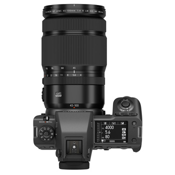 Top-down view of a mirrorless camera with telephoto lens attached and rear LCD screen visible.