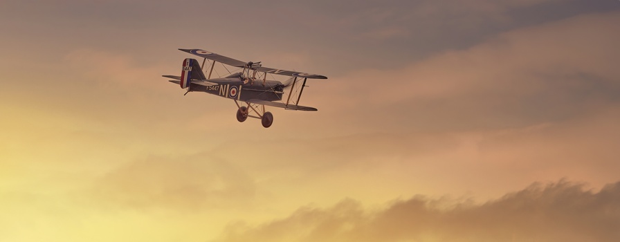 Vintage biplane silhouetted against golden sunset sky with warm atmospheric clouds.
