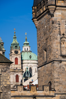 Historic stone church tower with ornate cupolas and golden domes under clear blue sky.