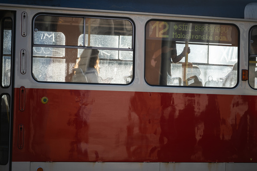 Side view of a red and gray public transit bus with passengers visible through windows.
