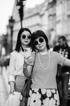 Two women in sunglasses pose together on a city street in this black and white portrait.