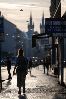 Woman jogging down a cobblestone street lined with historic buildings and storefronts at dusk.
