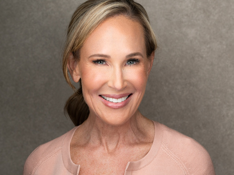 Professional headshot of a smiling woman with blonde hair against a neutral gray background.