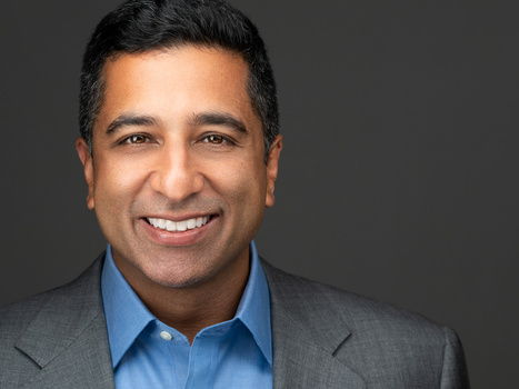 Professional headshot of a man in business casual attire smiling at camera.