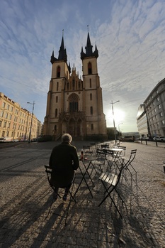 Person standing with bicycle in plaza facing twin-spired Gothic church at golden hour.