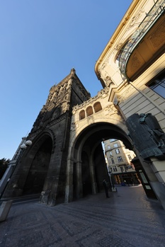 Gothic church facade with pointed arch entrance and ornate stone tower against clear blue sky.