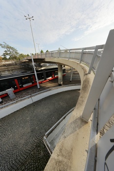 Elevated concrete overpass curved above a canal with red industrial equipment visible on the lower level.