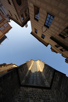 Upward perspective of historic stone buildings framing clear sky, shot from courtyard.