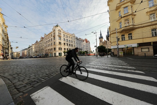 Cyclist crossing a zebra crossing on a wet stone plaza in an old European city square.