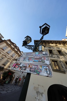 Upward view of vintage street lamps and ornate European building facades against clear blue sky.