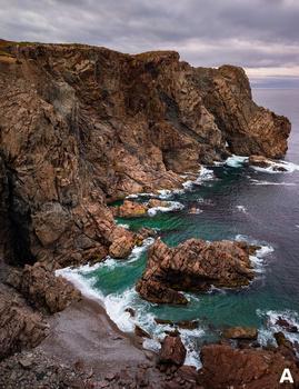 Rugged coastal cliffs with turquoise waves crashing against rocky formations.