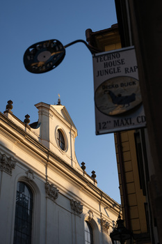 Street lamp with vintage sign against colonial architecture and blue sky.