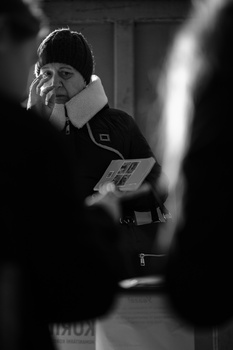 Photographer holding a light meter while checking exposure settings in black and white.