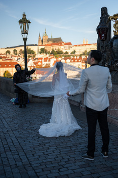 Wedding couple posing on a European cobblestone street with historic architecture in the background.