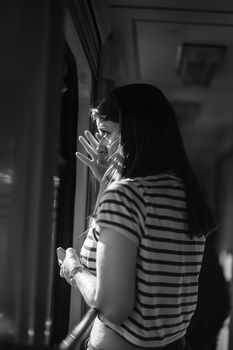 Woman in striped shirt adjusting her hair in a mirror, shot in black and white.
