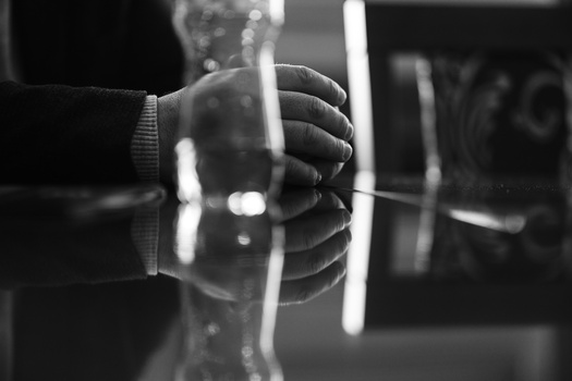 Gloved hands gripping a barbell loaded with weight plates in black and white.