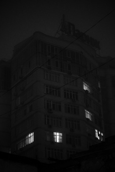 Dark gothic building at night with illuminated windows against a black sky.