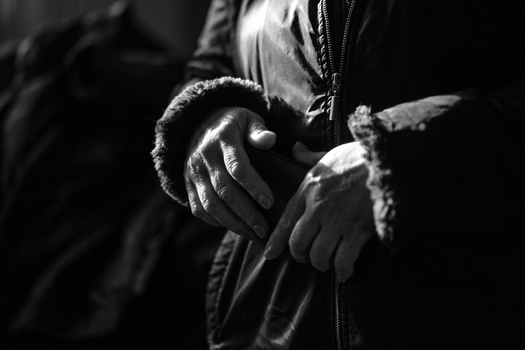 Gloved hands holding a small bird in dramatic black and white lighting.