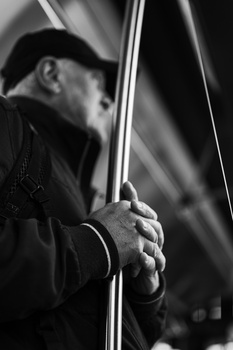 Hands gripping a vertical pole or rope, shot in black and white with dramatic side lighting.