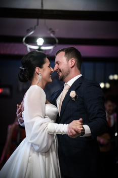 Bride and groom sharing their first dance at a reception, bathed in warm ambient lighting.