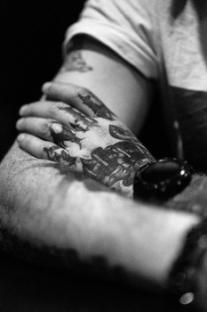 Close-up black and white photograph of hands with paint or artistic medium applied to skin and clothing.