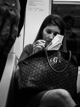 Woman on public transit holding a transit card near her face in black and white street photography.